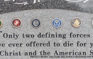 Close-up of illicit use of official military branch emblems on Christian memorial in violation of DoD regulations