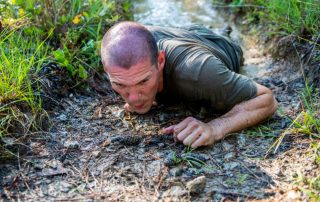 Army Ranger student crawling through mud