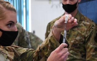 Medical service member filling syringe to vaccinate soldier