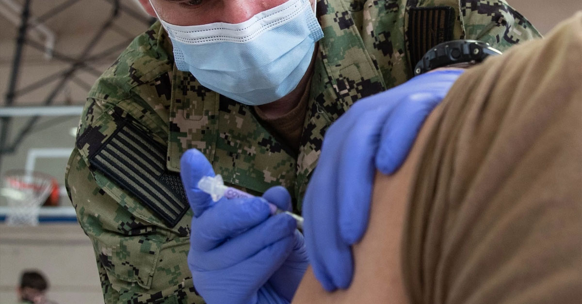 U.S. Navy servicemember administering COVID vaccine to the arm of another servicemember
