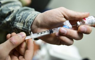 Close up of hands filling a vaccine syringe