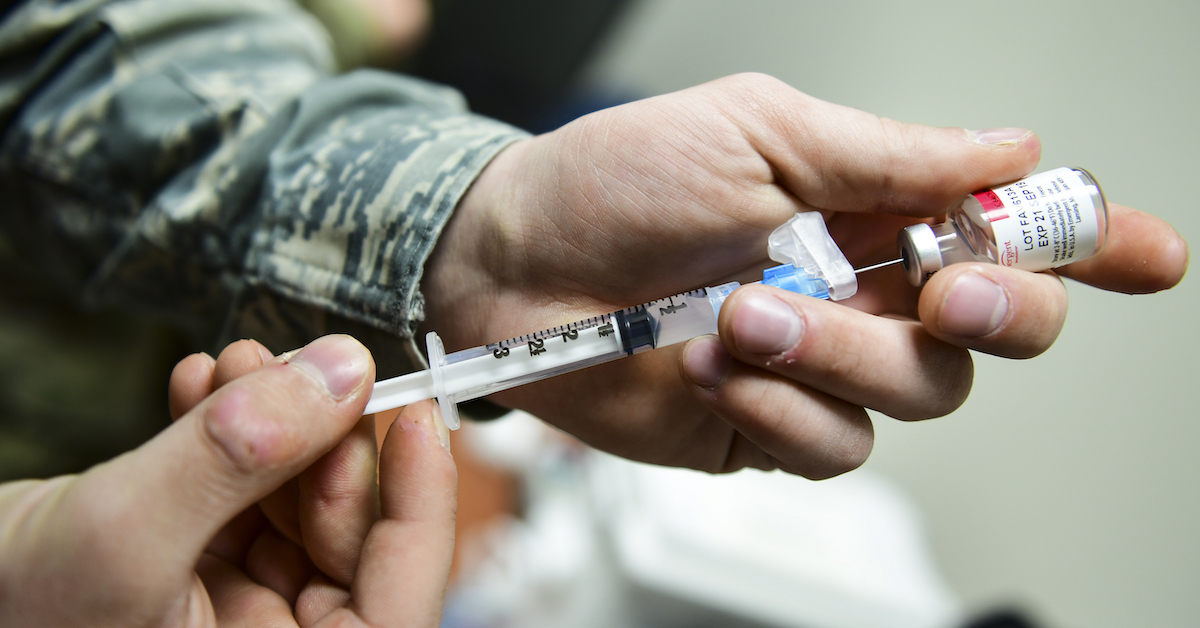 Close up of hands filling a vaccine syringe