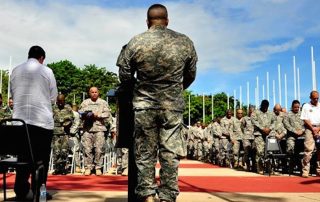 Chaplain shown from behind praying to crowd