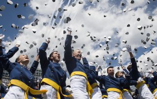 Graduating Air Force Academy cadets throw hats into the air