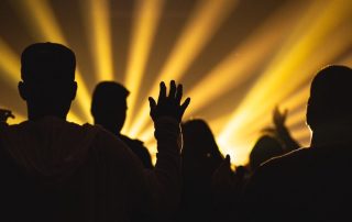 Creepy silhouette of people from the back with hands raised towards glowing beams of light