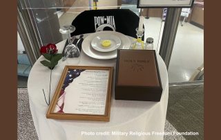 Photo of POW MIA table showing that the Bible on it is enormous. Bigger than the size of the dinner plate and covering about a third of the width of the table.