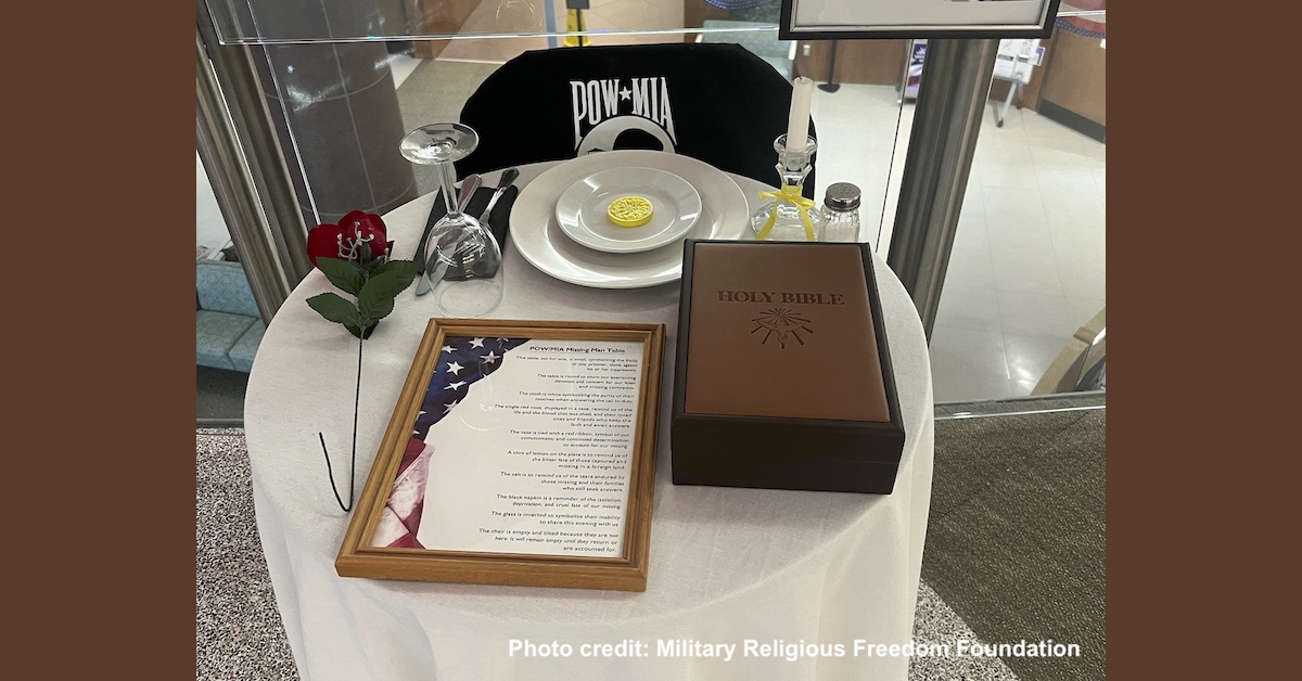 Photo of POW MIA table showing that the Bible on it is enormous. Bigger than the size of the dinner plate and covering about a third of the width of the table.
