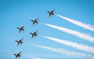 Six F-16 Fighting Falcon aircraft with contrails against a clear sky.