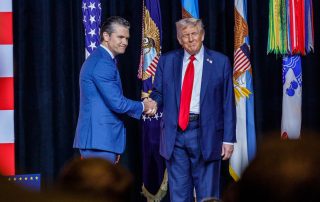 Hegseth shaking Trump's hand on stage at Quantico meeting